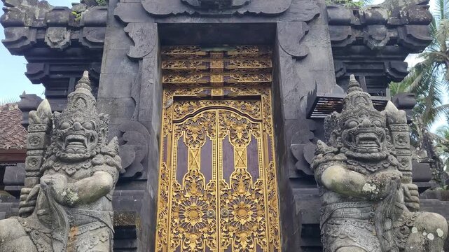 The golden gate of a Hindu temple in a village in Bali, Indonesia, with its protective dvarapala demons.