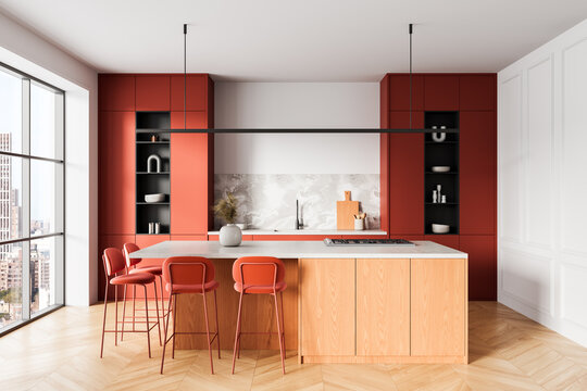 Modern kitchen interior with red cabinets and minimalist island in bright apartment space, city view through large window, elegant design concept background. 3D Rendering