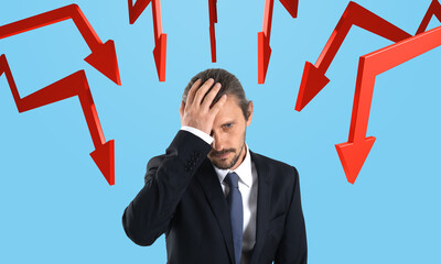 Worried businessman holding head surrounded by red downward arro