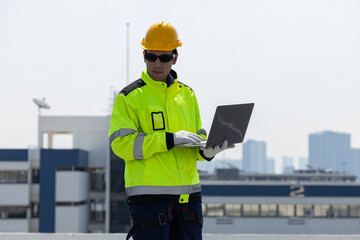 Obraz premium Engineer inspecting solar panels using laptop on rooftop