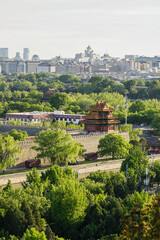 Fototapeta premium Beijing,Aerial view of traditional Chinese architecture surrounded by greenery with a modern city skyline in the background