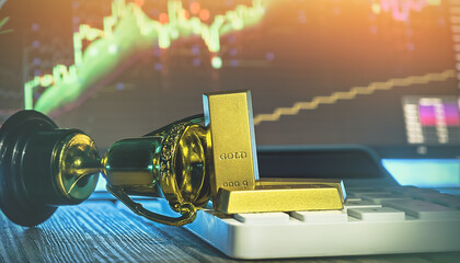 Fallen trophy with gold bars on keyboard and stock market chart background, concept of trading loss, investment failure, market risk, financial failure and business stress.