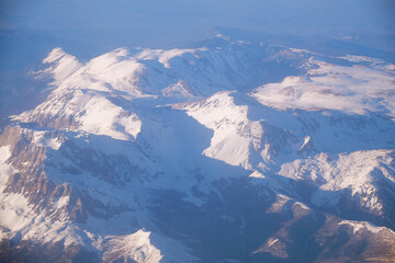 Caucasus mountains with snow peaks in aerial winter scene. Aerial view from plane.