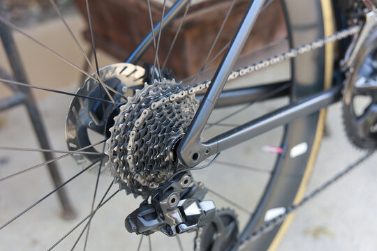 Detailed closeup shot black bicycle rear wheel featuring cassette gear derailleur chain mechanical part parked outdoor showing active lifestyle concept urban transport cycle maintenance close