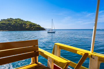 Obraz premium View from a ferry deck of a white sailboat anchored in the calm blue bay of Koh Samed, Rayong, Thailand