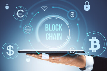 Digital blockchain concept with cryptocurrency and finance icons above a tablet held by a businessman on a futuristic technology background.