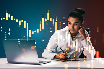Businesswoman analyzing financial chart data on laptop while taking notes, with glowing candlestick graph overlay on dark gradient background.