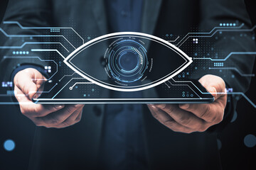 Futuristic digital eye interface displayed on tablet held by businessman in suit, representing cybersecurity and surveillance concept.