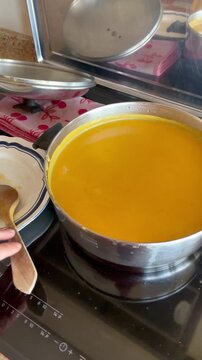 Caldo y crema de calabaza en cazuela de cocina y plato de cuchara de madera dando vueltas