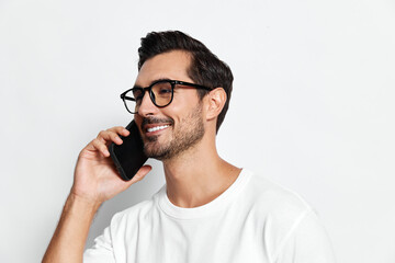Smiling man wearing black glasses speaks on mobile phone with cheerful expression, isolated on...
