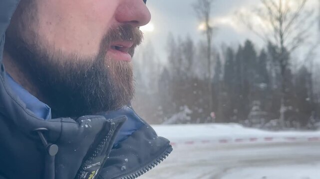 Close-up of a man smoking, video. A man with a beard in a winter jacket.