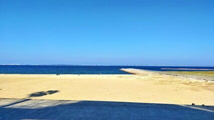 秋の青空が広がる白い砂浜と穏やかな海の風景