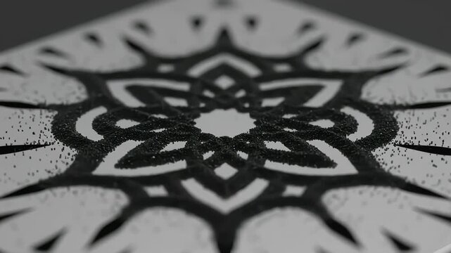 Close-up of black sand falling through a template to form a symmetrical geometric mandala design