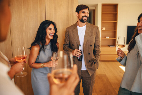 Group of friends enjoying drinks and laughing indoors during a casual event