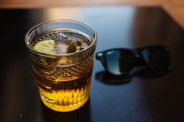 Glass of cocktail with sunglasses in the background