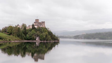Zamek w Niedzicy nad jeziorem w mglisty dzień &ndash; spokojny krajobraz z odbiciem w wodzie