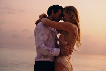 Wet newlyweds embracing at sunset by the sea