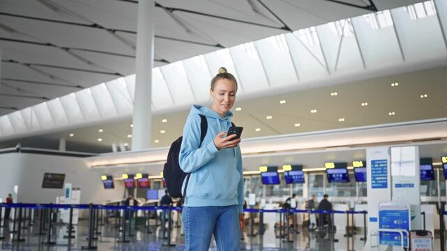 White Woman Casually Checks Her Mobile Device For Aircraft Information Amidst Busy Terminal Environment