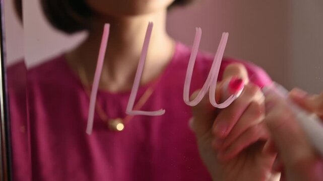 Love note. Girl Drawing ILU, lovely message on a Heart on a Mirror and Blowing a Kiss for Valentines day
