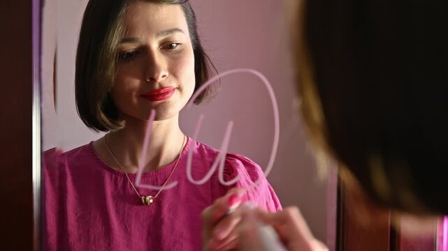 Love note. Girl Drawing LU, lovely message on a Heart on a Mirror and Blowing a Kiss for Valentines day