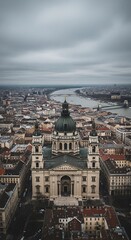Elevated view captures grand basilica architecture overlooking expansive urban landscape and flowing river under overcast sky