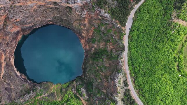 Round sinkhole lake and road in Croatia aerial view