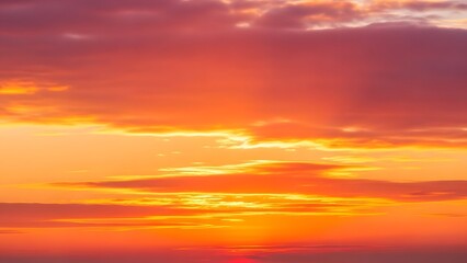Obraz premium Vibrant sunset paints the sky with fiery orange and gold hues, casting a warm glow over the horizon