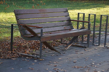 Ławka zniszczona, zdemolowana w parku miejskim przy chodniku  © Sławek