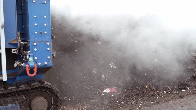 Waste processing plant of organic waste. The aerator of the industrial conveyor system processed the organic waste with the steam rising inside. Close-up of organic waste processing