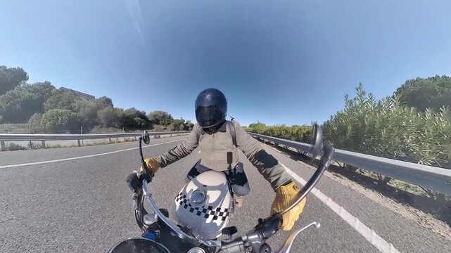 Chico con casco oscuro en motocicleta cl&aacute;sica rodando por carretera y bosque en d&iacute;a soleado ,toma grabada en 4k