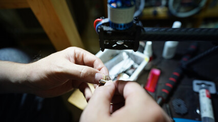 Close-up of a technician&rsquo;s hands repairing machinery with tools and components.