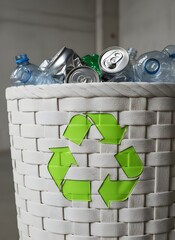 White woven basket with recycling symbol filled with plastic bottles and cans