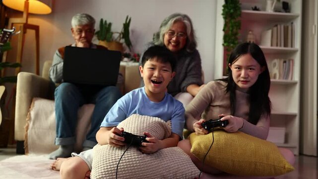 teasing. sisters and brothers are having fun teasing each other. Asian sibling having fun playing game. Happy Family leisure activity with parents and children playing video game living room at home