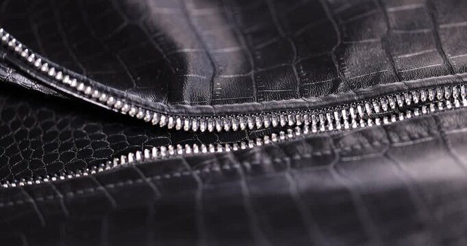 black artificial fabric in the style of crocodile skin with specks and spots, a close-up of a piece of clothing made in the style of leather
