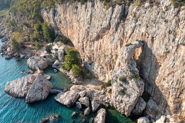 Scenic coastal view of rocky cliffs and calm water with a small boat near a beach in a natural setting