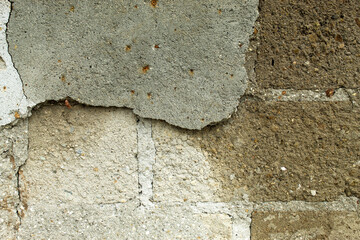 Old concrete wall with peeling plaster revealing the brickwork underneath