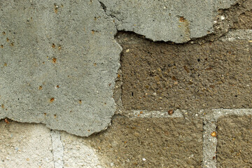 Old concrete wall with peeling plaster revealing the brickwork underneath