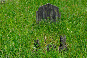 Brockenhurst, UK - May 31st 2025: Gravestones in the long grass in St Nicholas&rsquo; Churchyard.