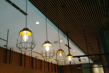 Low-angle shot showcasing a series of retro-style pendant lights suspended from a modern ceiling, highlighting interior design and architectural elements within a contemporary space.