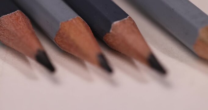 a row of black wooden pencils folded on cheap loose paper, wooden pencils with lead for drawing or other work