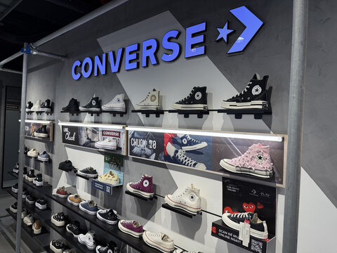 Converse store retail display wall with blue CONVERSE arrow logo sign and shelves showcasing multiple Chuck Taylor All Star high-top sneakers, Vietnam, Cam Ranh, January 17, 2026