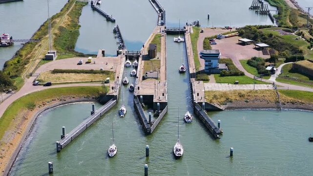 several sailboats navigate through lorentzsluizen lock complex kornwerderzand narrow stone walled chambers connect fresh ijsselmeer water salt afsluitdijk netherlands to 