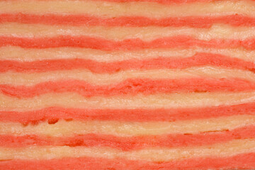 Macro view of raw homemade pasta dough showing a textured pattern of alternating red and yellow horizontal stripes