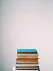 Fototapeta premium A stack of books with various colored covers resting on a white surface. Ideal for educational and literary themes.