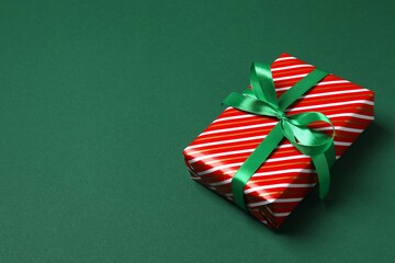 Beautiful Christmas gift box with ribbon on green background