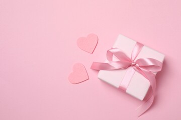 Beautiful gift box with pink hearts on color background
