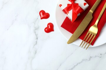 Elegant Valentine&rsquo;s-themed table arrangement featuring plate, gift box, and golden cutlery. Top view, space for text