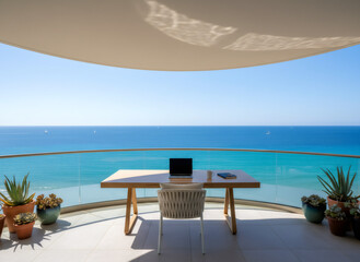 Obraz premium Laptop and notebook on a table on an outdoor balcony overlooking the ocean. Remote work setup for a digital nomad lifestyle.