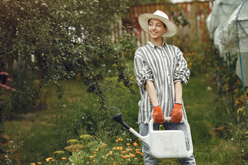 Women pours flowers in the garden with watering can