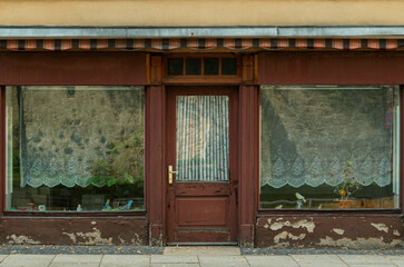 Old closed storefront with weathered facade and large display windows